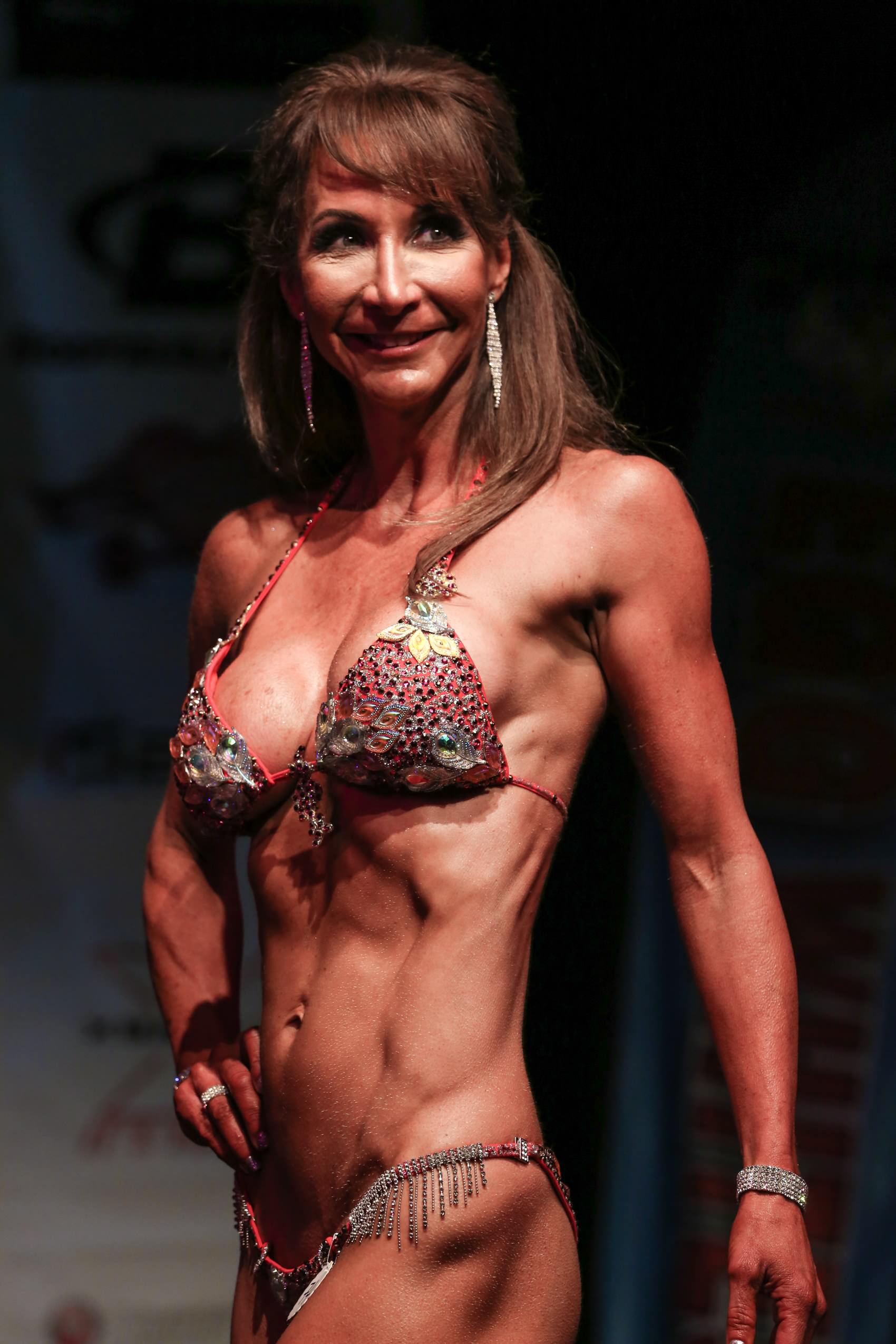 Lynn Montoya posing during a figure competition, showcasing muscular definition and stage presence.