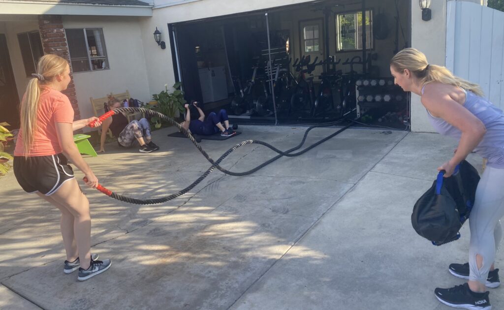 Women over 40 using battle ropes and sandbags during an outdoor strength training session
